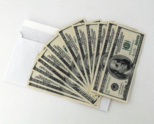 An envelope filled with $100 bills, symbolizing what a personal loan is